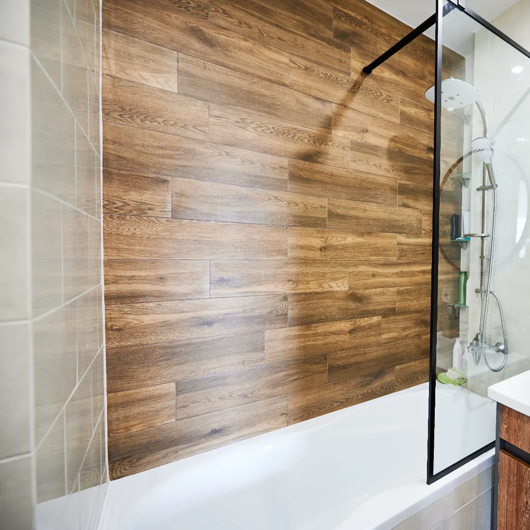 Salle de bain avec carrelage effet bois et paroi de douche vitrée
