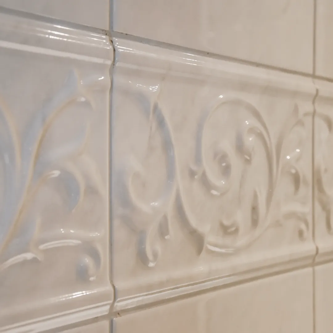 Frise décorative en relief sur carrelage mural beige